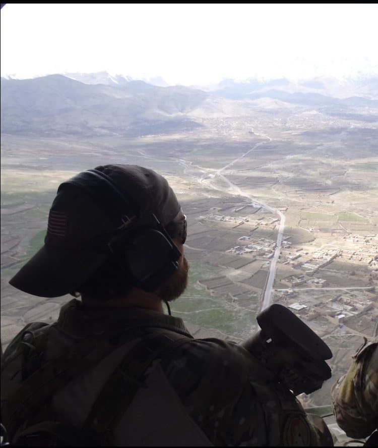 A service member looks out over a valley from a ridgeline